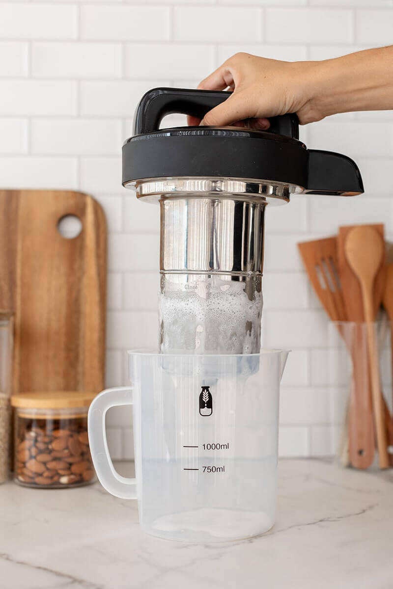 Pouring foam from Mylky machine's stainless steel filter into a measuring jug
