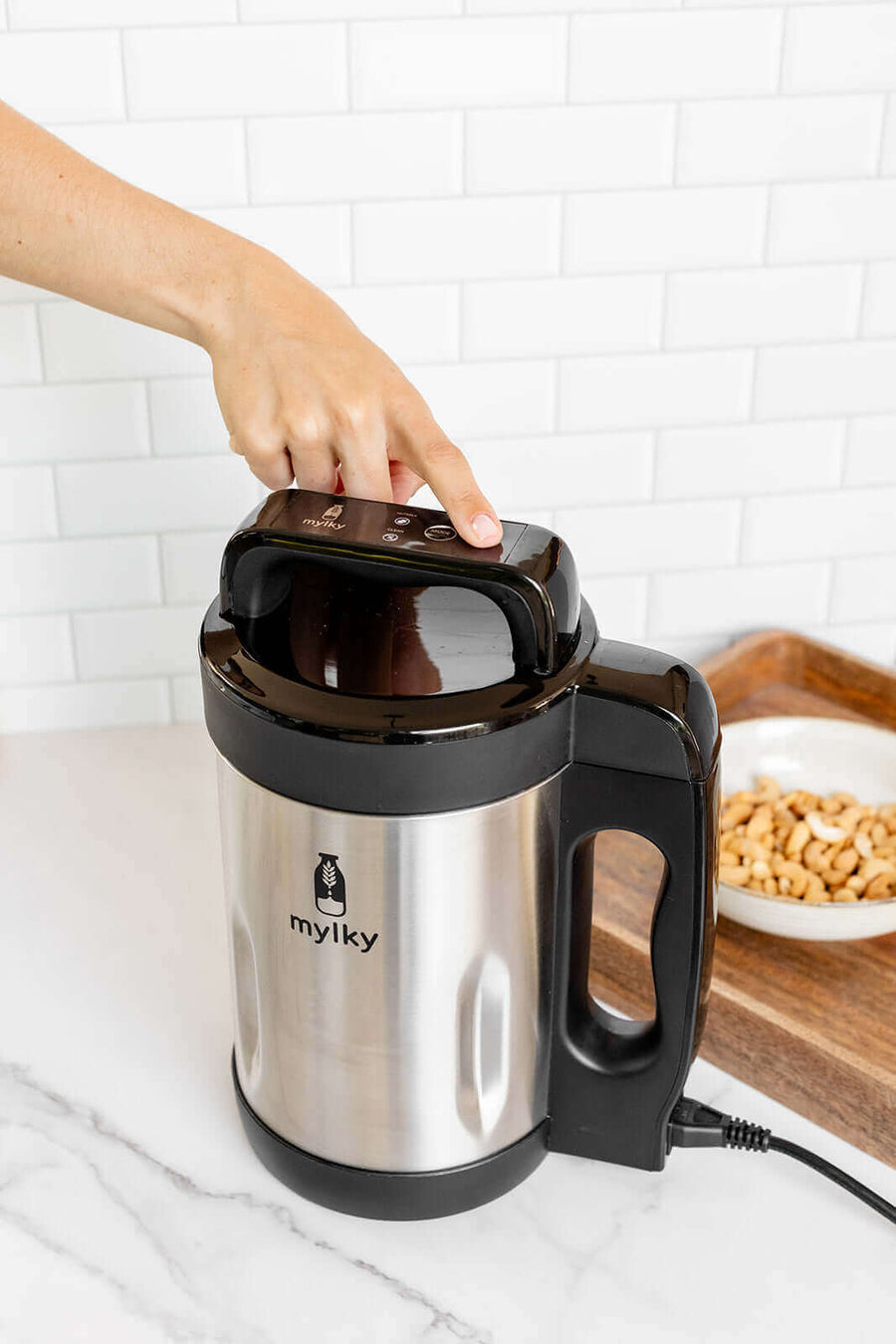 Person pressing button on stainless steel Mylky machine