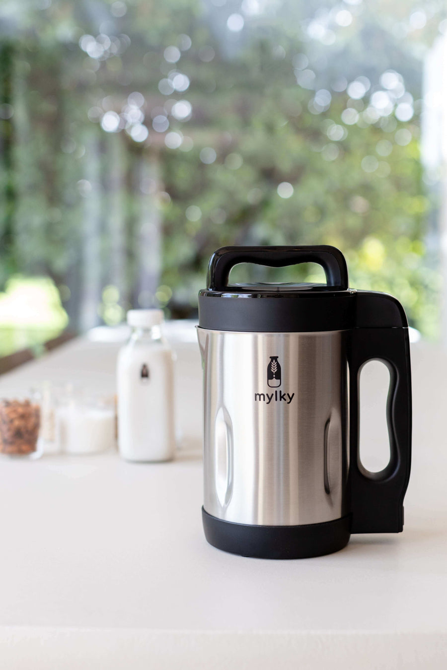 Mylky stainless steel plant-based milk maker on a kitchen counter with bottles and ingredients